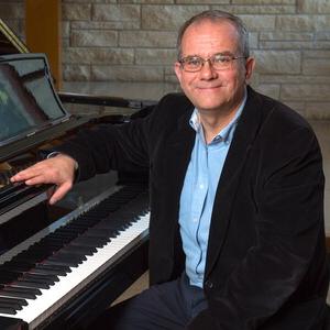 Dr. Slawomir Dobrzanski sitting at a grand piano.