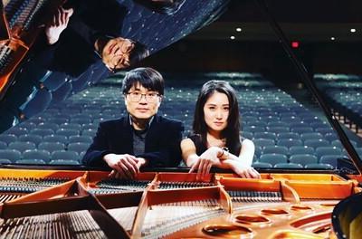 Feifei Jiang and Peter Jiang sitting at a grand piano.